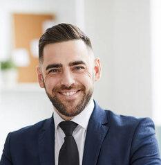 stock-photo-young-successful-businessman-formalwear-looking-you-smile-while-sitting-workplace